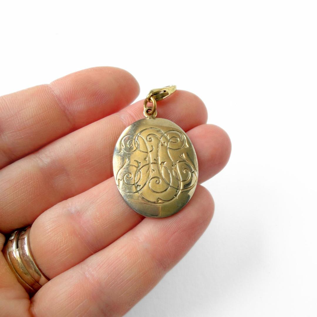 Vintage gold tone decorative monogram-like oval charm