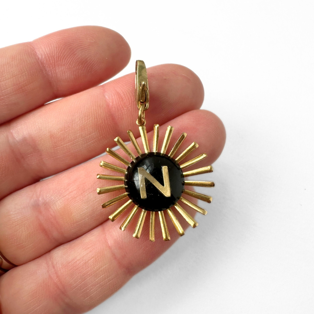 Vintage black glass "N" monogram sunburst charm