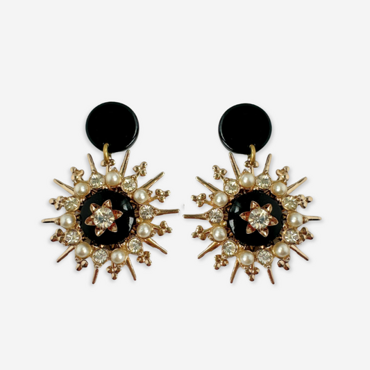 Pair of earrings with black centers, pearl-like beads, and gold accents on a white background