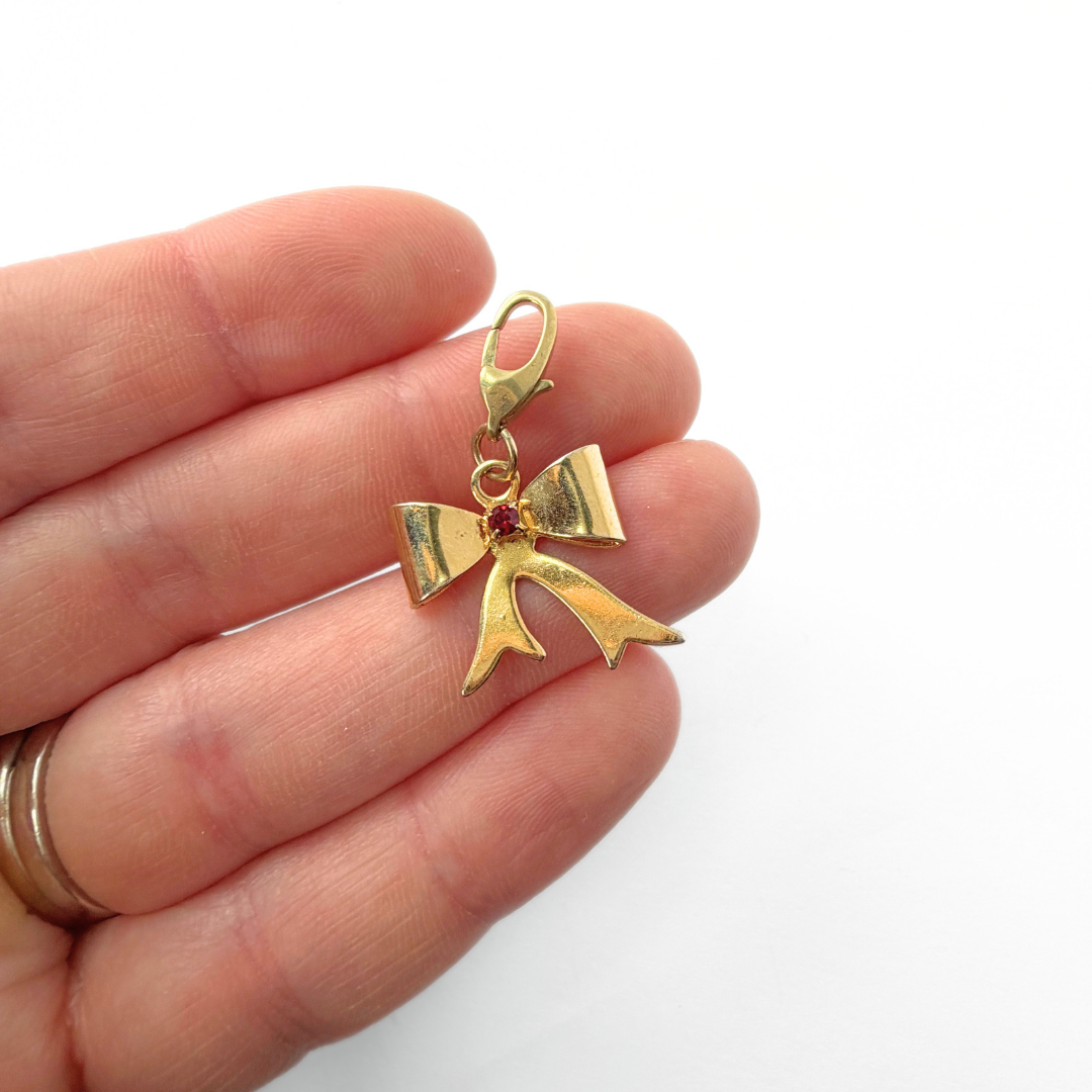 Vintage small gold plated bow charm with red center