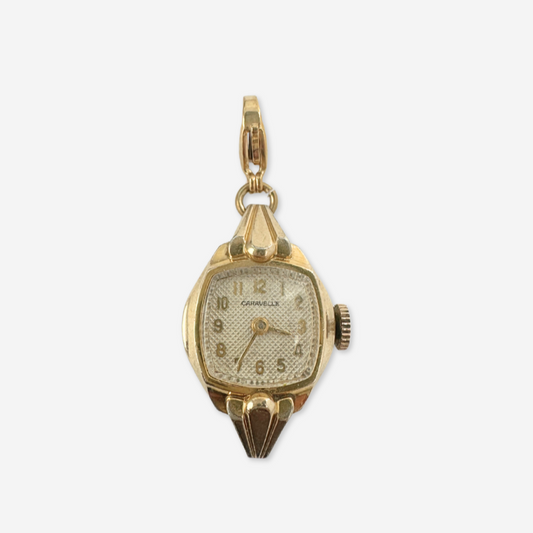 Gold watch charm on a white background