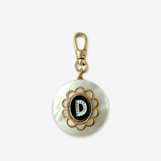 Decorative keychain with a circular design featuring a letter 'D' on a white background