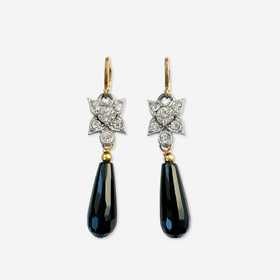 Pair of earrings with black teardrop stones and diamond accents on a white background