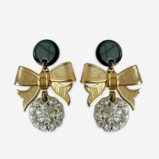 Pair of gold bow earrings with black centers and crystal details on a white background