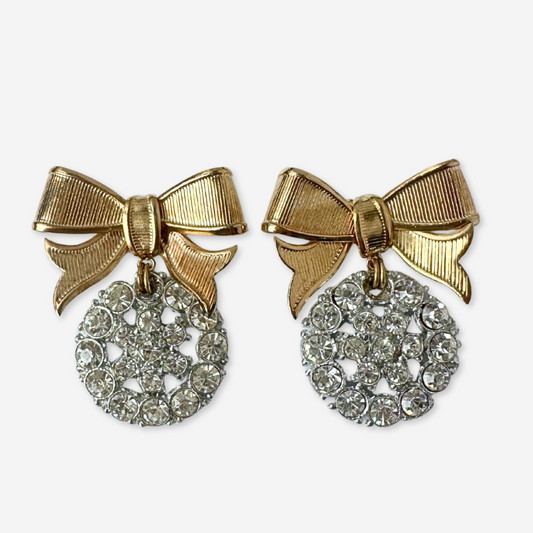 Pair of earrings with gold bows and diamond-like centers on a white background