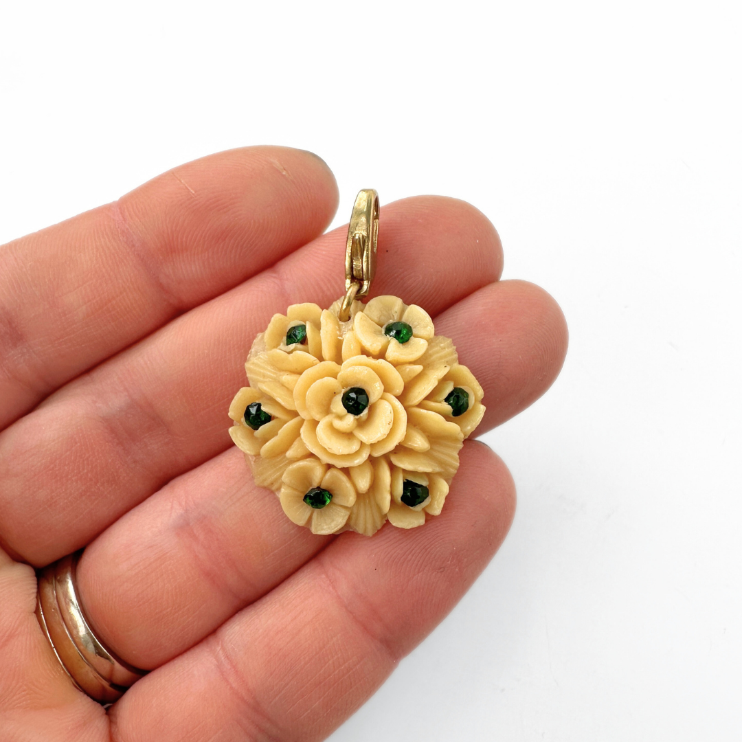 Vintage pale yellow carved celluloid flower charm with green rhinestones