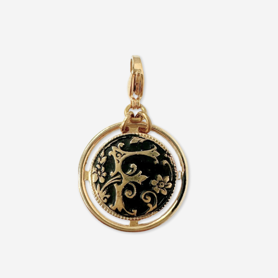 Large black and gold ornate letter "F" circular charm