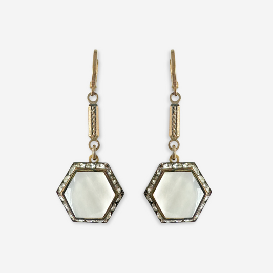 Hexagonal earrings with white centers and gold accents on a light gray background