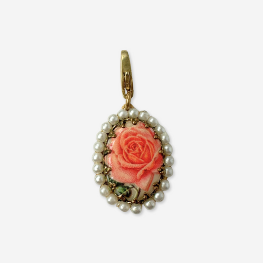 Vintage-style pendant with pink rose and pearl accents on a white background