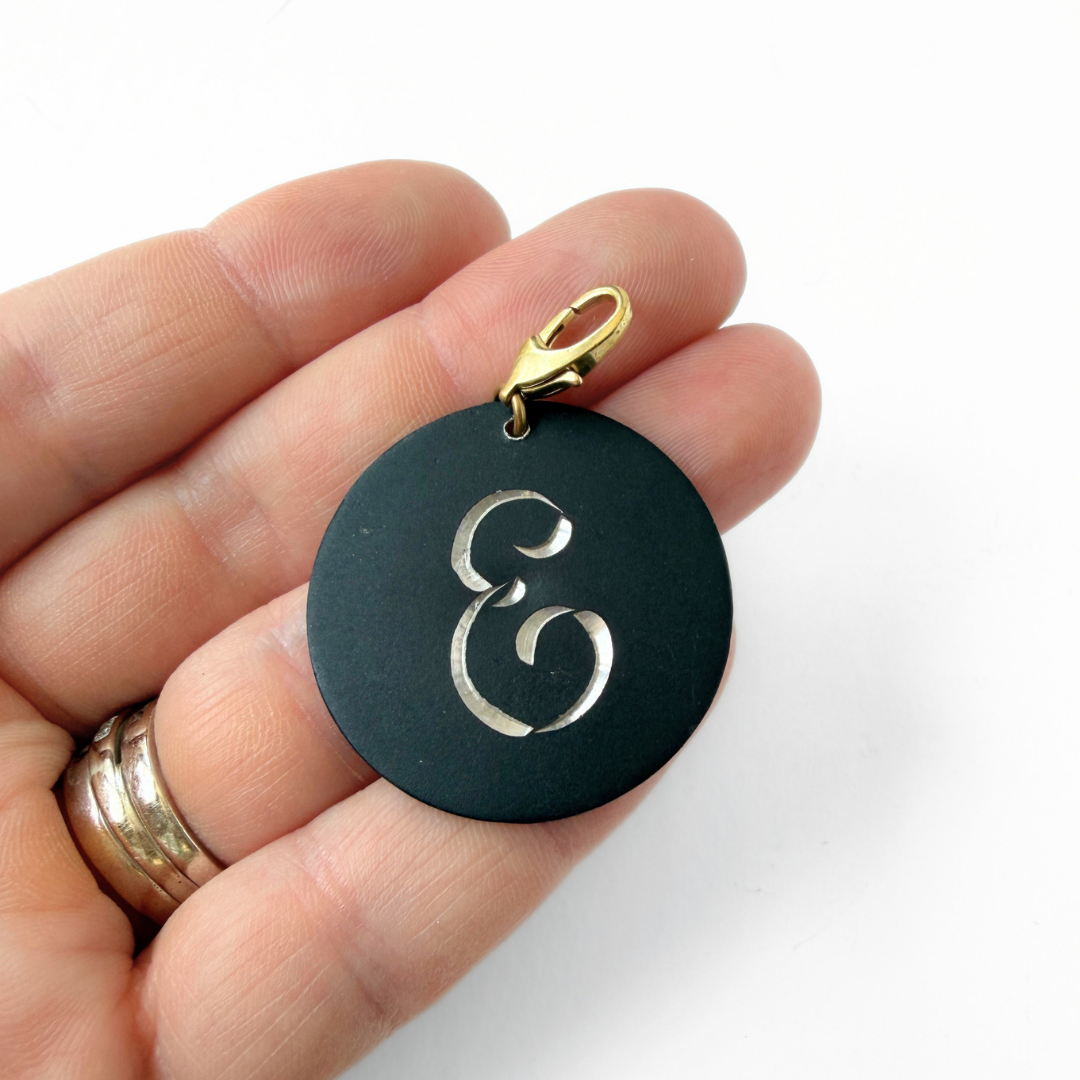 Large vintage black matte circular "E" monogram charm