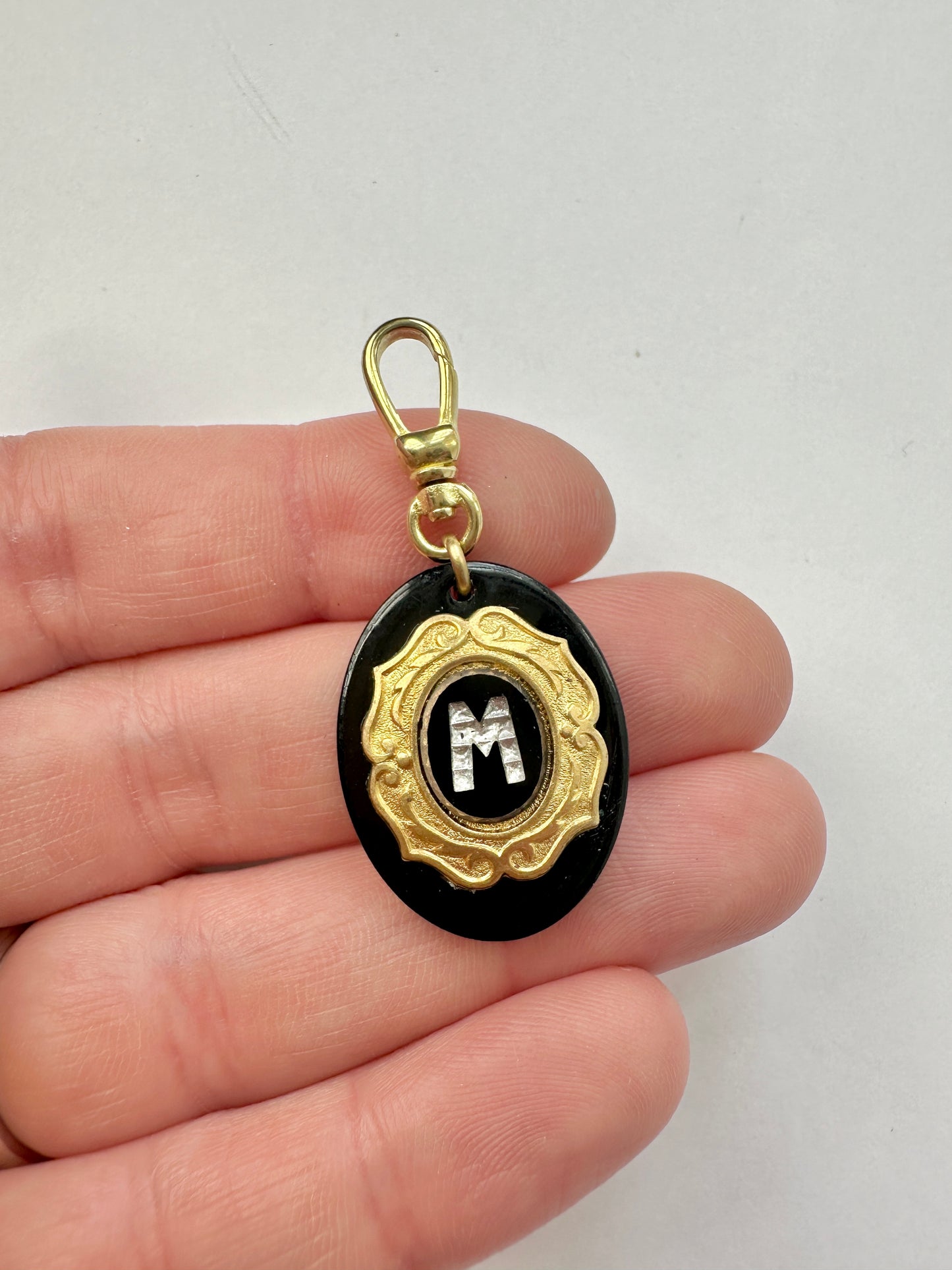 Vintage letter "M" black and brass layered oval charm